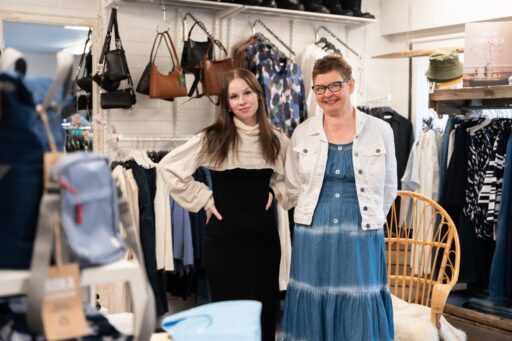 Äiti ja tytär seisovat vierekkäin vaatekaupassa.
