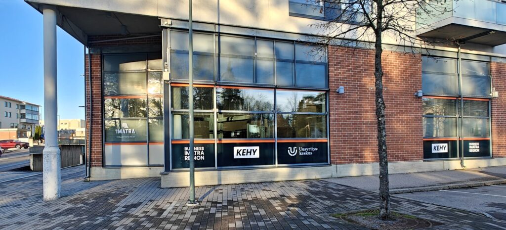 Katutasossa kulmassa liiketila, jossa Business Imatra Region ja KEHYn sekä Imatran kaupungin teippaukset.