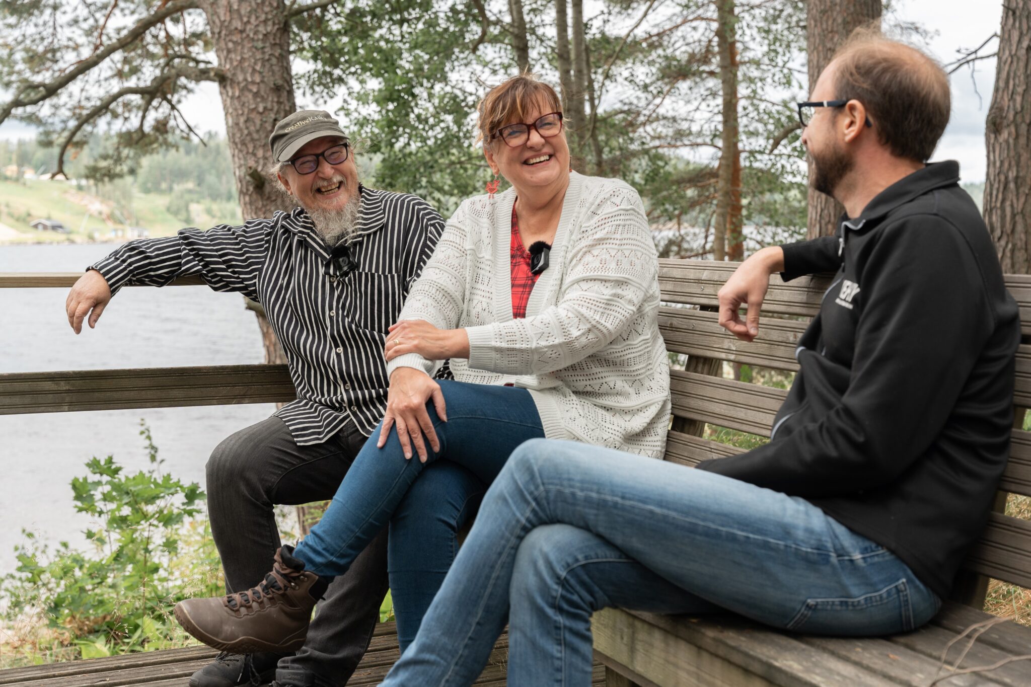 Virve ja Jari Niiranen sekä Sven Langbein istuvat ulkona penkillä.