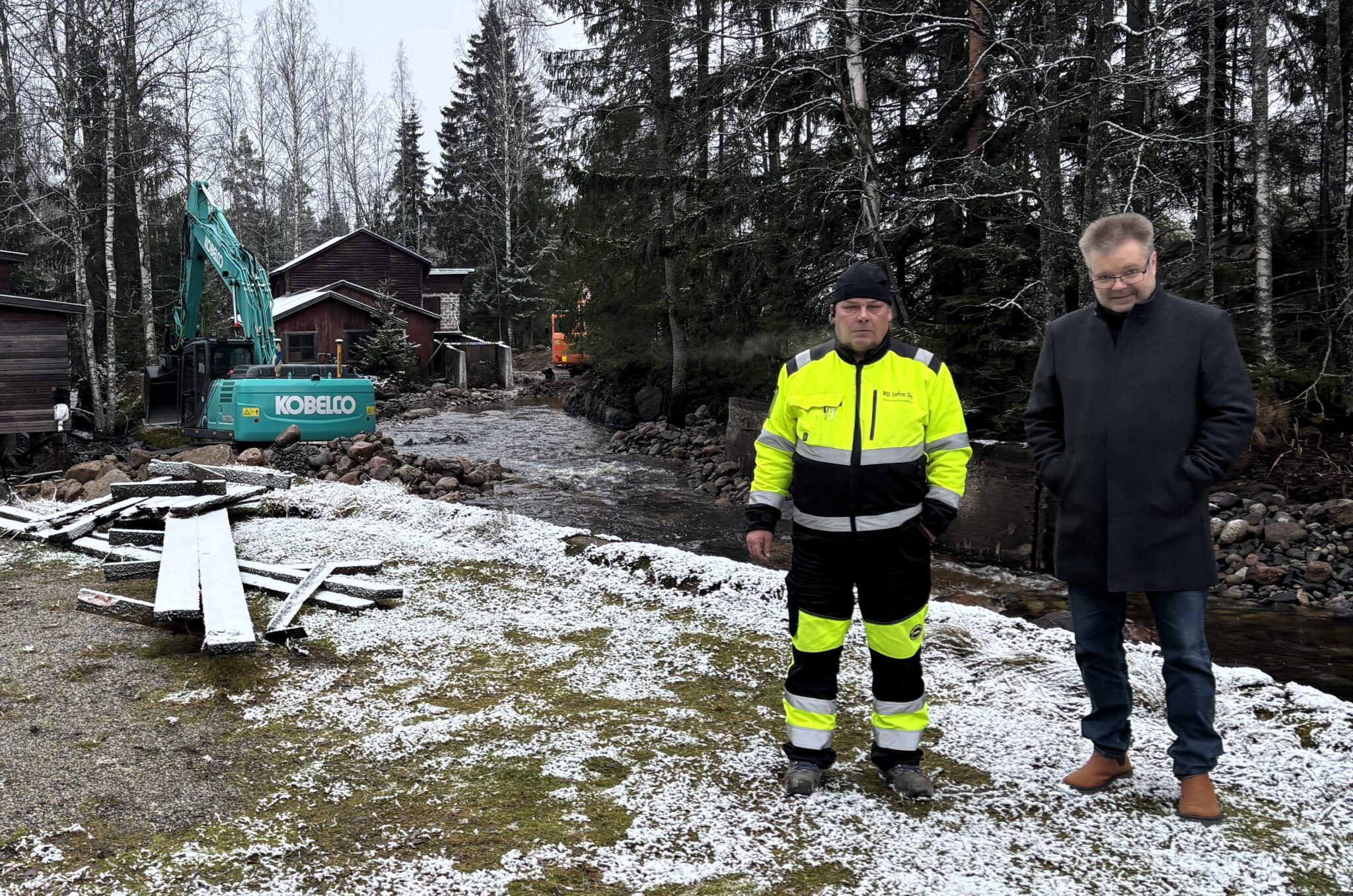 Huomioasuinen yrittäjä ja yritysasiantuntija kuvassa, taustalla metsää, koskea ja kaivinkone.